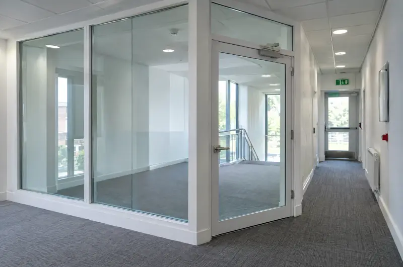 Fire-rated glazed screen on an escape corridor. Fire-rated glazed screen and door in an office escape corridor (illustrative)