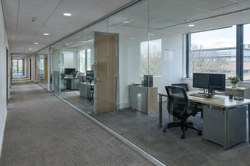 Single glazed frameless run along a corridor. Frameless single glazed glass partition running along an office corridor (illustrative)
