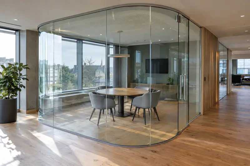 Curved frameless glass room. Curved frameless glass partition forming a rounded meeting room (illustrative)